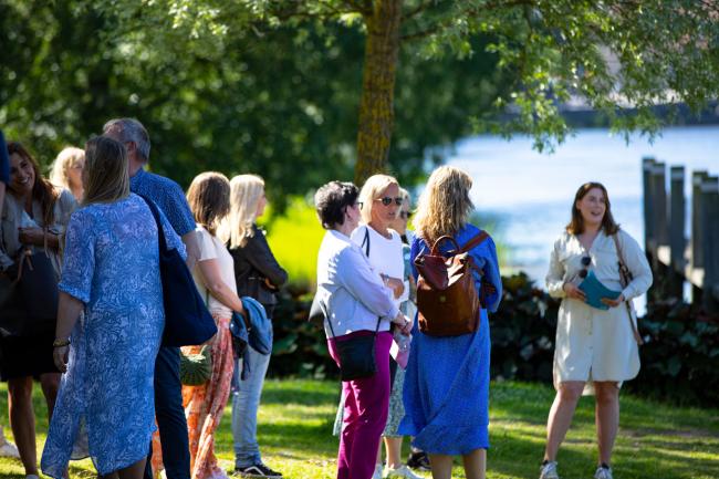 folk står under träden och lyssnar på en kvinna.