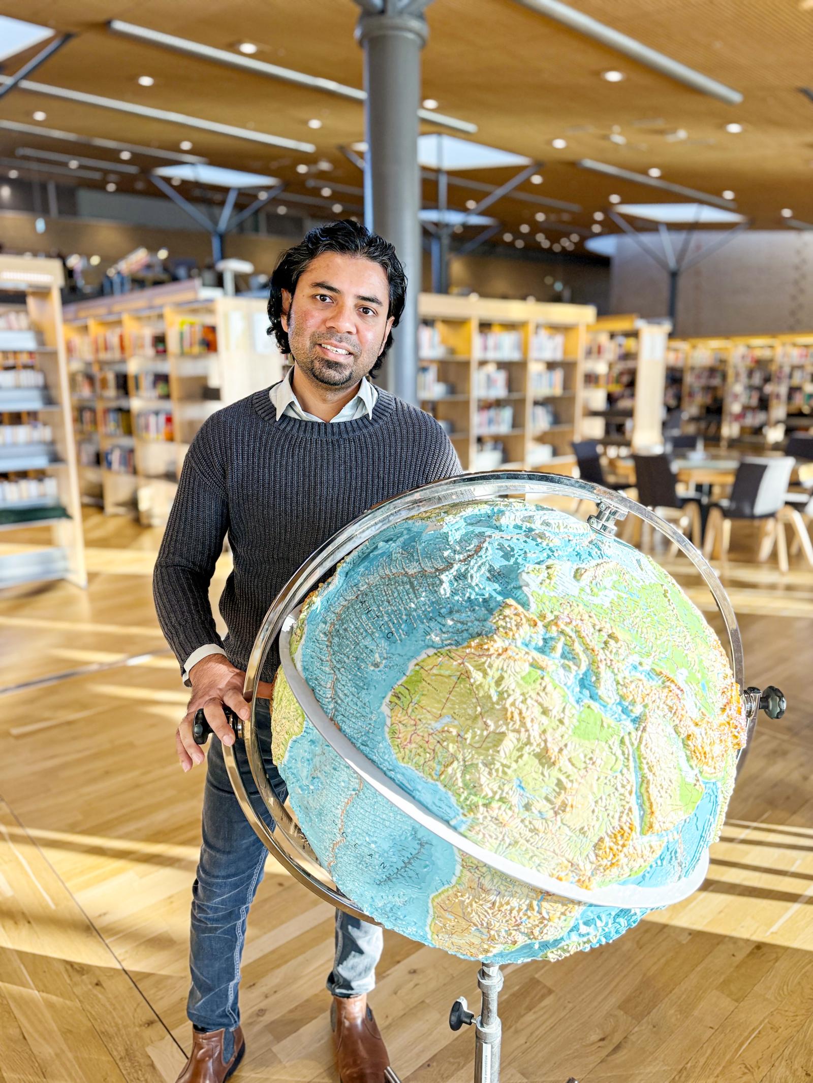 Avit Bhowmik stående vid jordglob