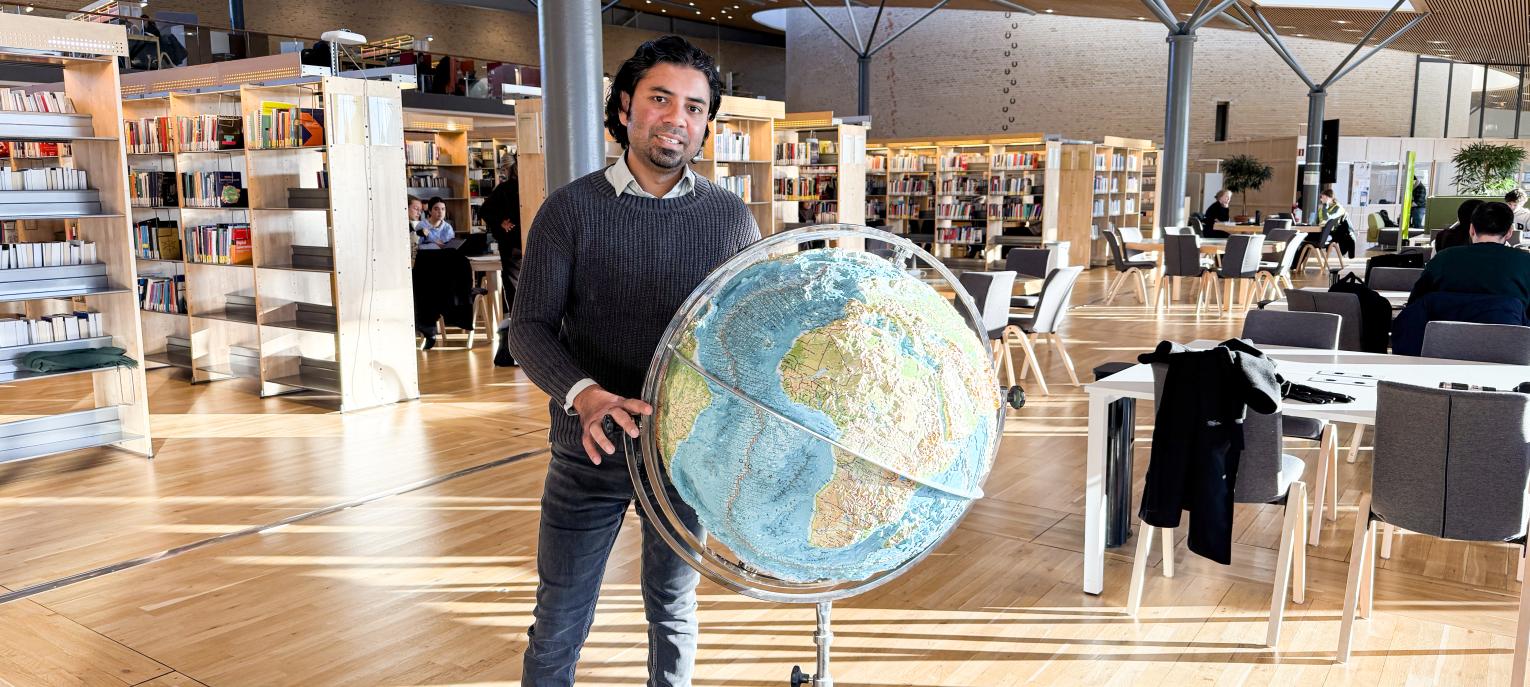 Avit Bhowmik med jordglob i biblioteket