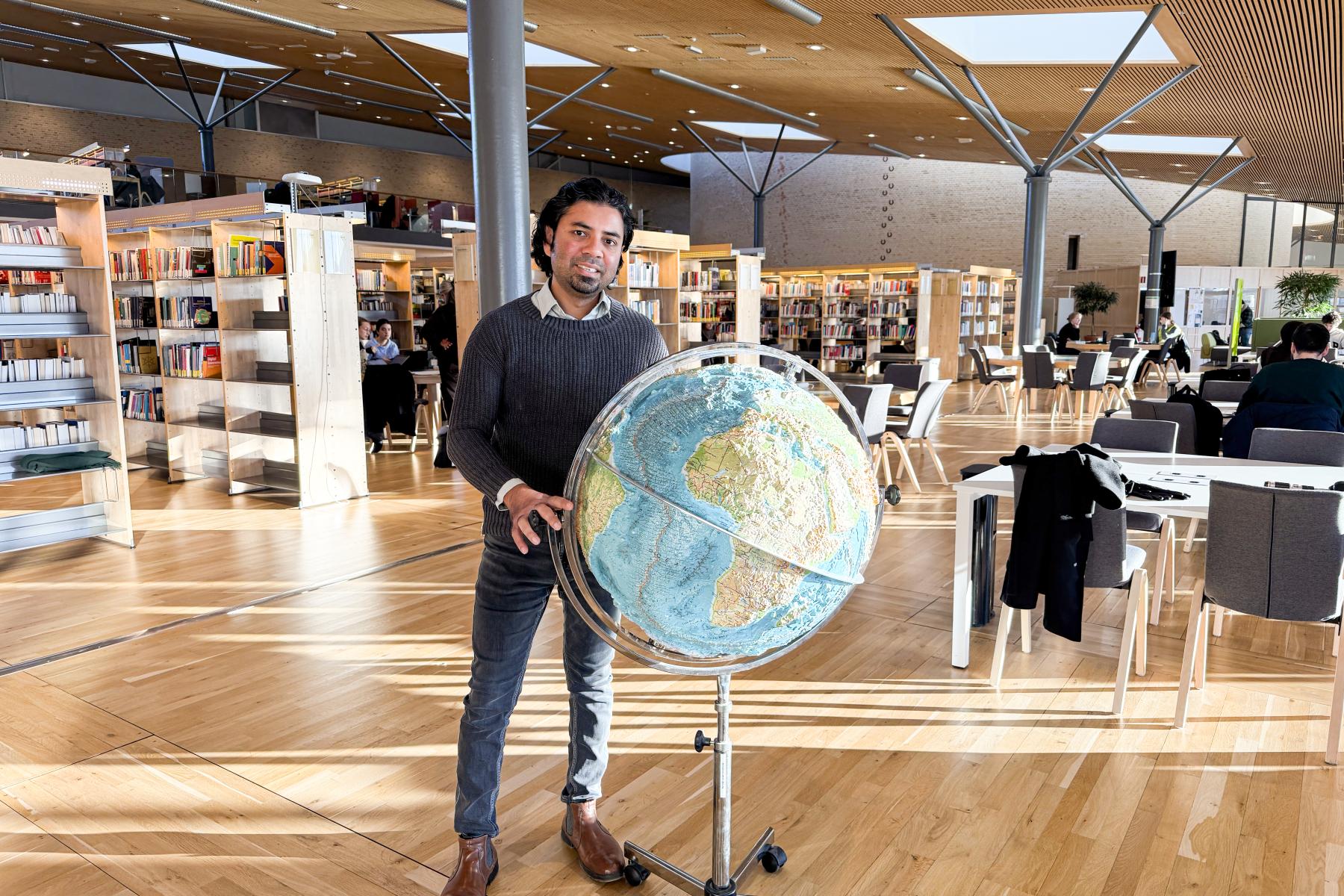 Avit Bhowmik med jordglob i biblioteket